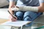 Disabled woman with bandaged arm signing document concept